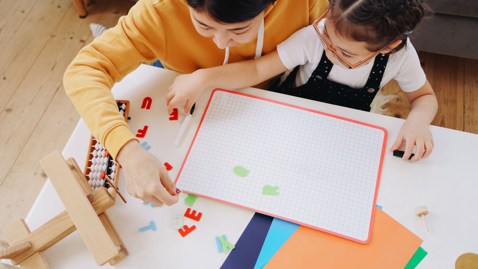 A mother and daughter learn at home using manipulatives.